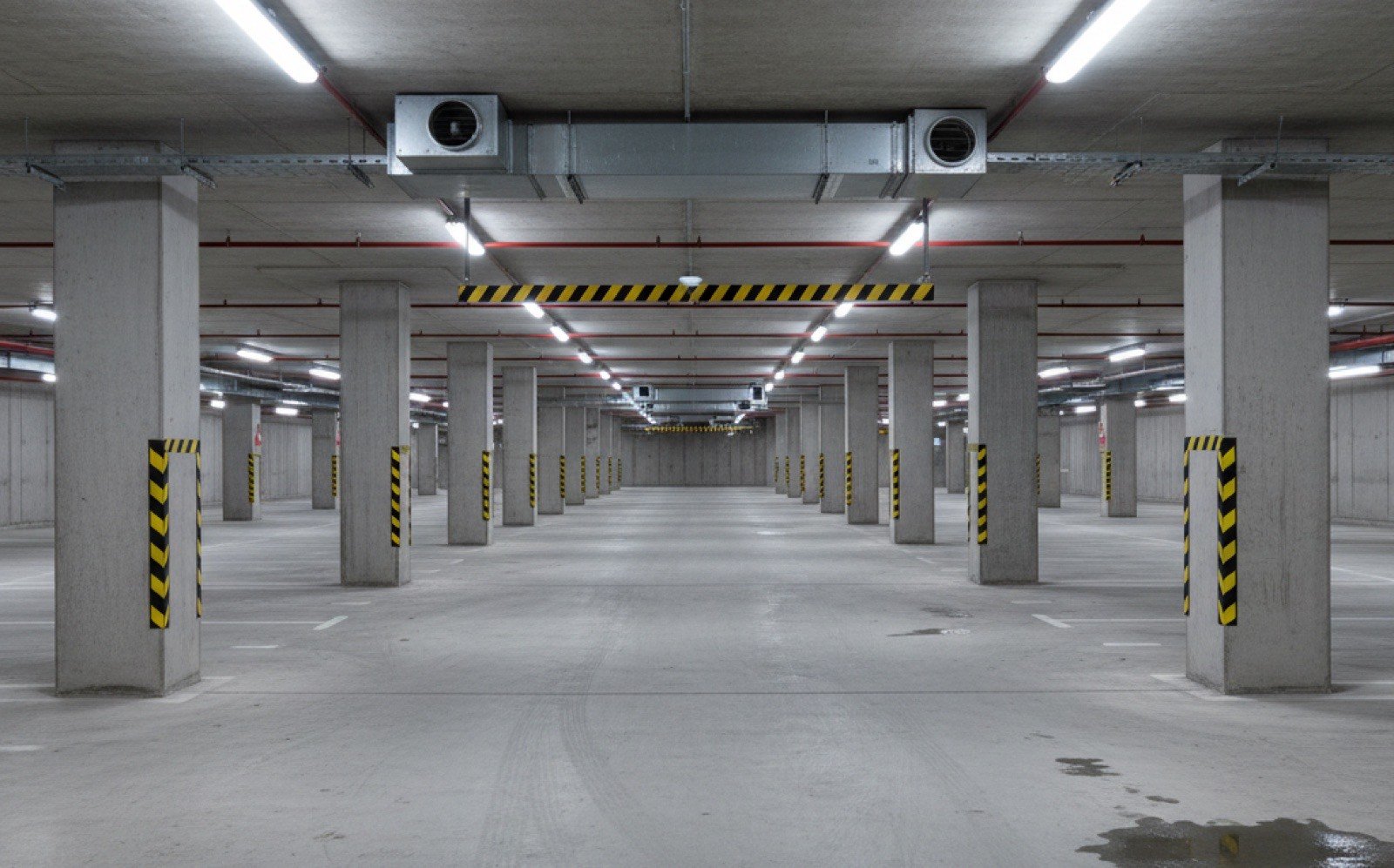 Leere Tiefgarage mit Sichtbeton-Stützen und schwarz-gelb markierten Anprallschutz-Streifen